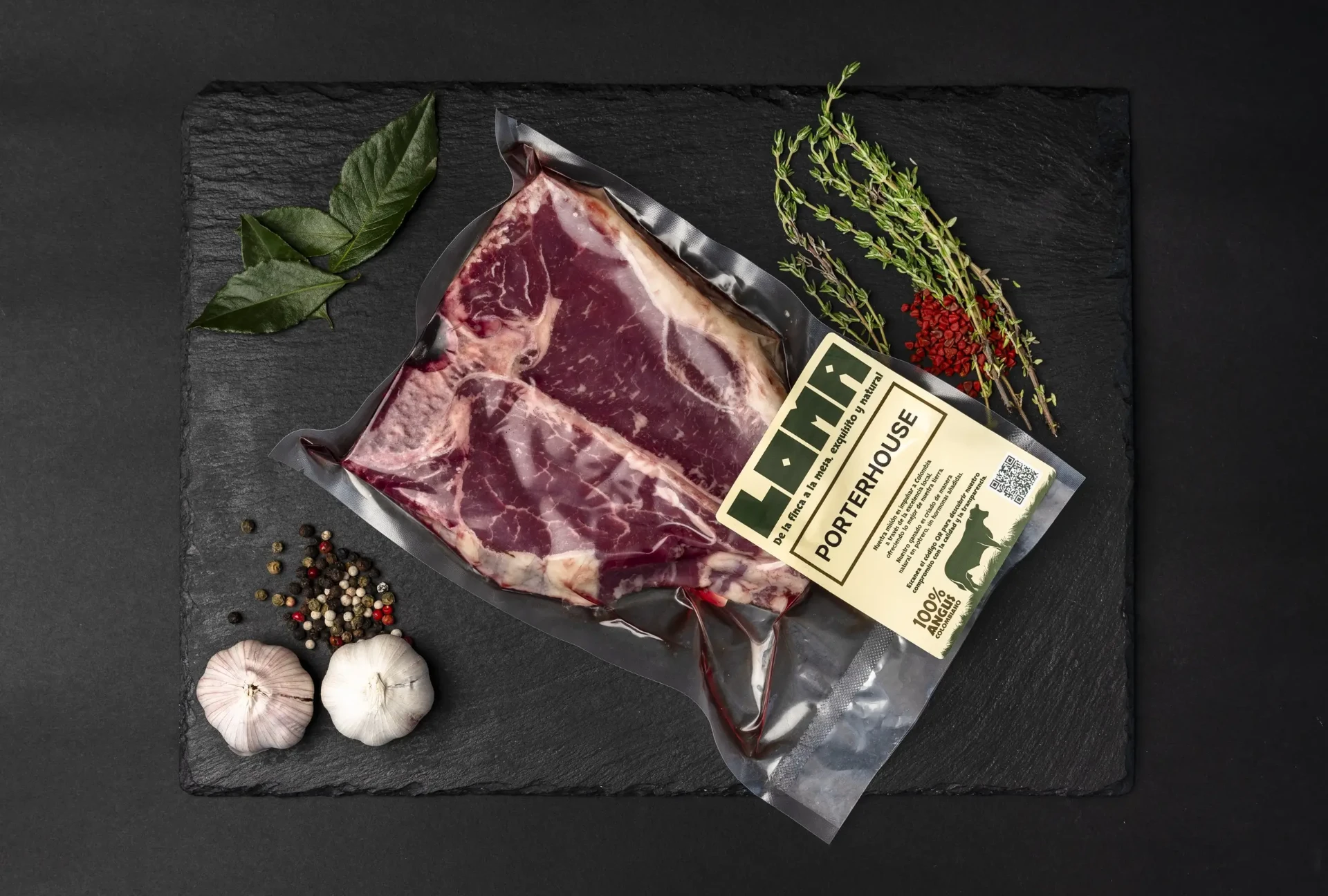 Corte Porterhouse de Angus colombiano LOMA sobre pizarra negra, con la etiqueta 100% Angus colombiano a la vista